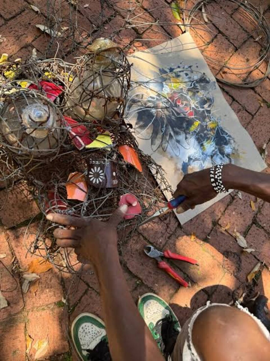 The artist twisting wire with pliers on a brick courtyard