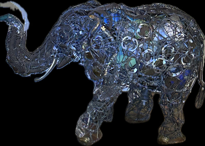 Elephant sculpture in salvaged wire and found metal, lit against black