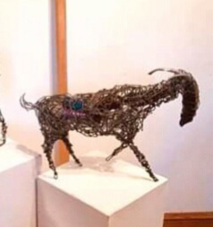 Ram with curved horns, built from wound wire, shown on a plinth